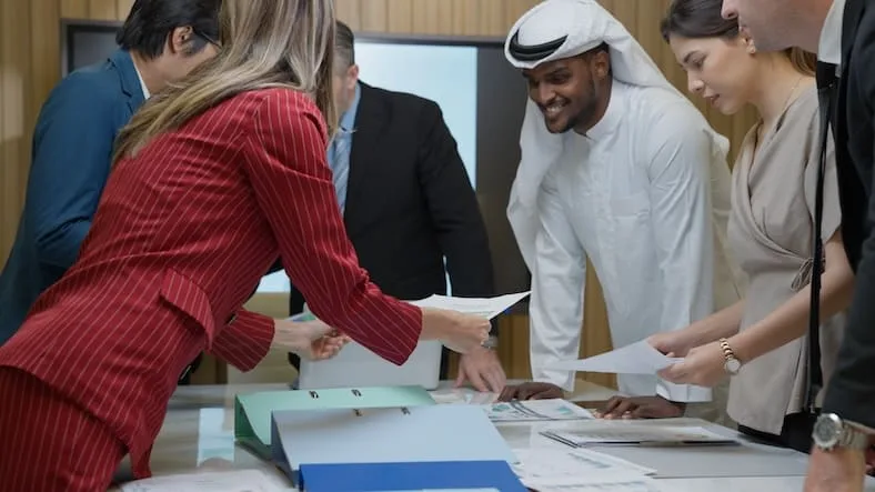 Personnes, dont un Émirati, échangeant des documents pour illustrer l’obtention du certificat de résidence fiscale aux Émirats