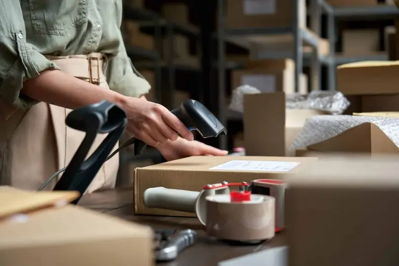 Vendeuse scannant un colis e-commerce dans un entrepôt – dropshipping à Dubaï