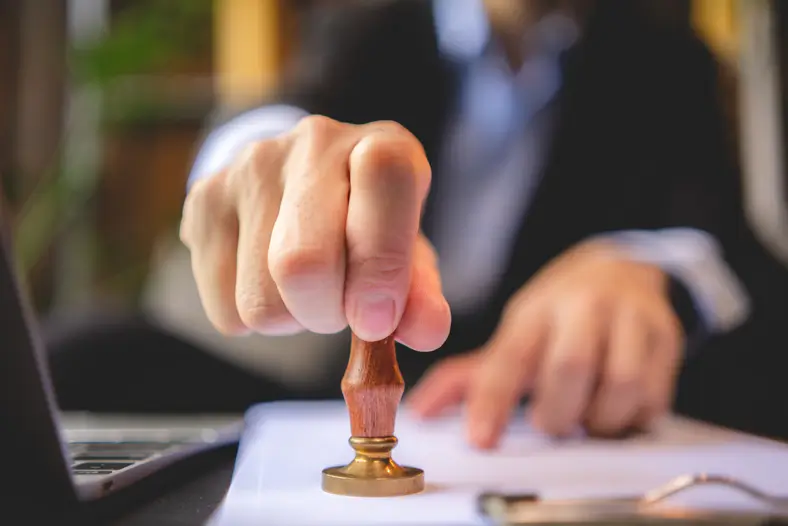 Main apposant un tampon d'approbation sur un document – entreprise immobilière à Dubaï