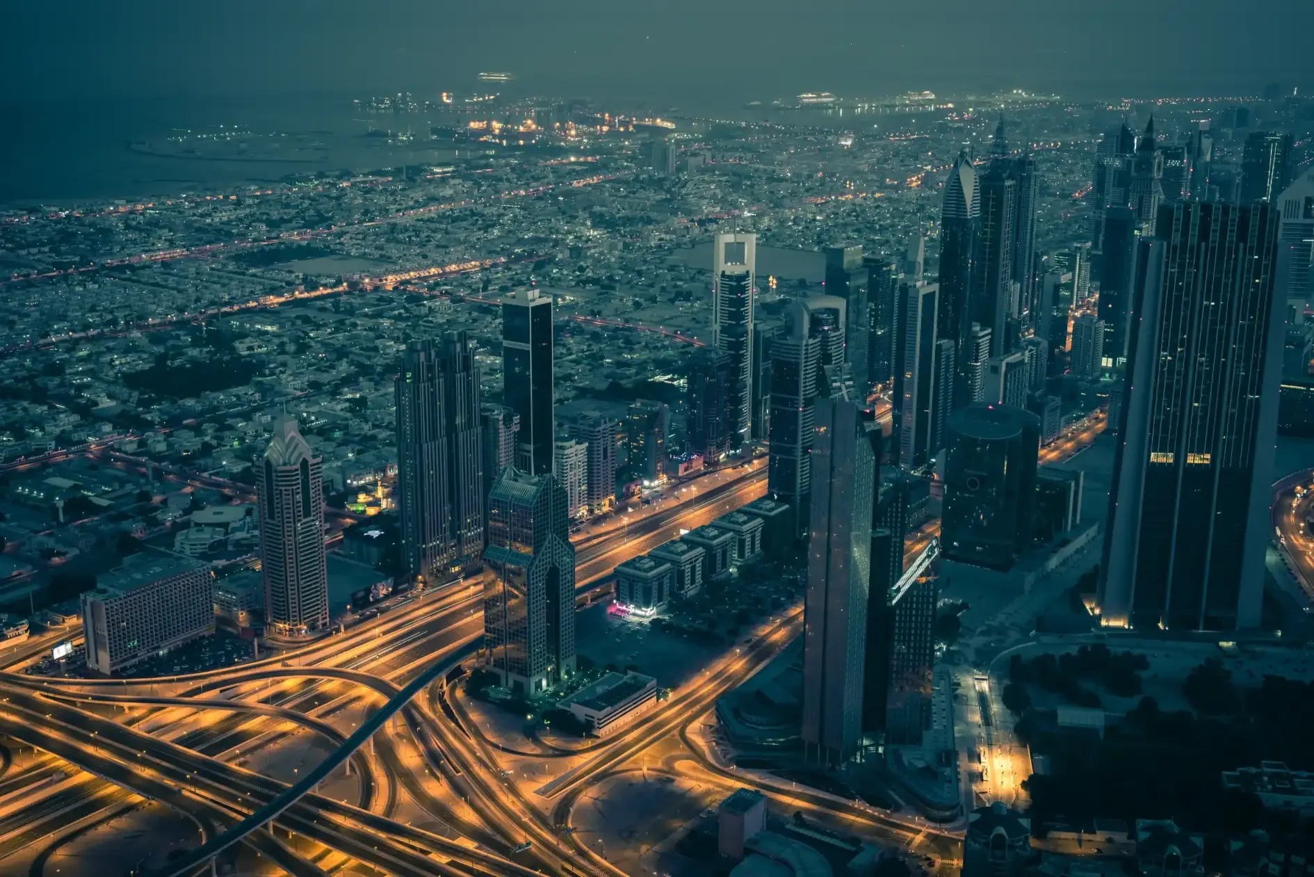 Dubaï de nuit : skyline et routes pour illustrer le choix du nom de société Vue aérienne de Dubaï de nuit avec gratte-ciel et échangeurs routiers
