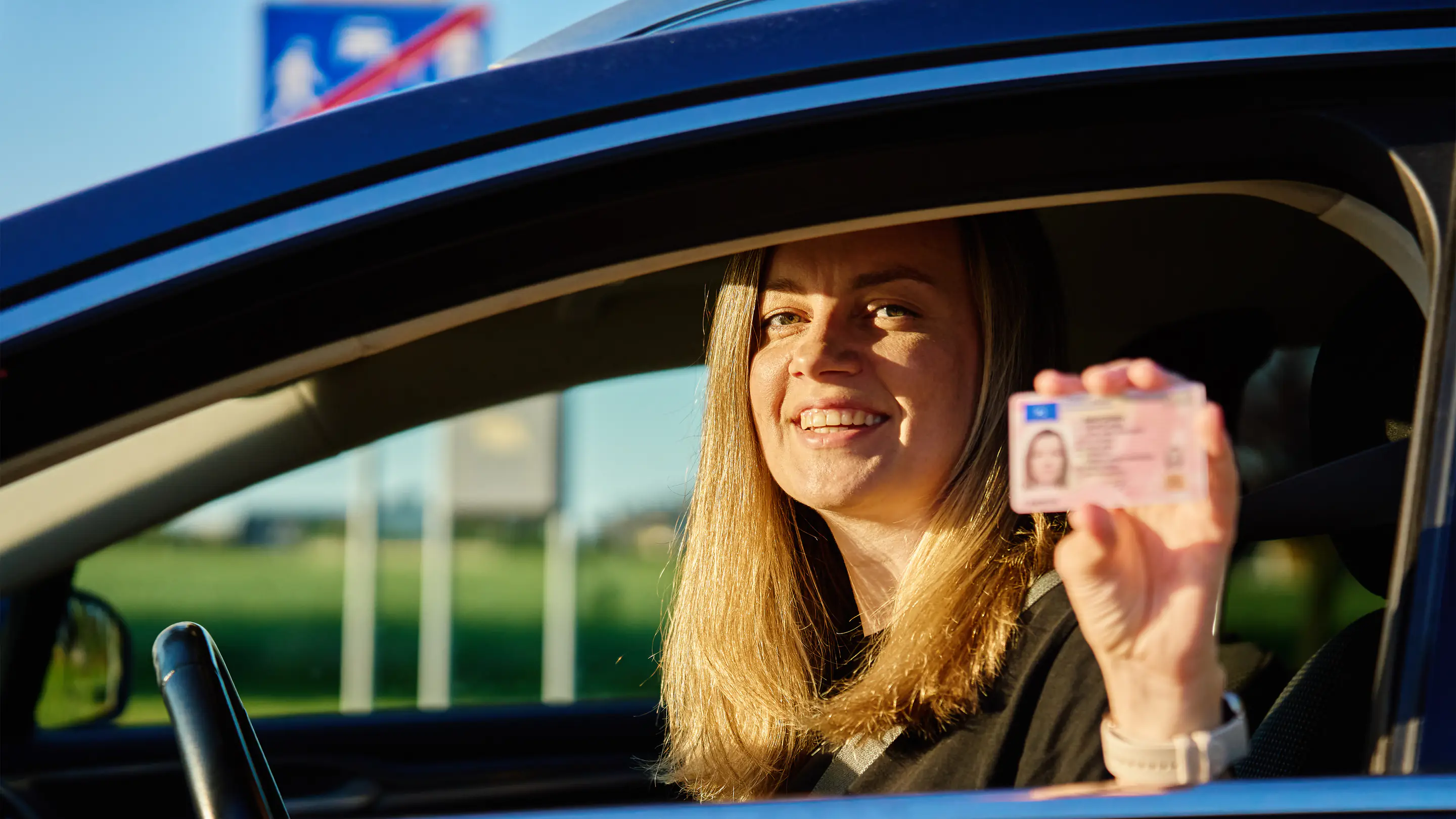 Conductrice souriante tenant son permis de conduire
